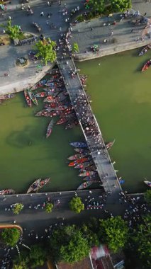Hoi An, Vietnam 'da yoğun bir köprünün demirlediği geleneksel teknelerin kavramsal insansız hava aracı görüntüleri. Seyahat tanıtımları, Asya turizmi ve kültürel yaşam tarzı görüntüleri için ideal.