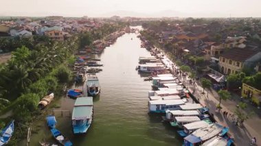 Hoi An nehrinin, Vietnam 'ın renkli teknelerinin ve nehir kenarındaki pazar hayatının yüksek kaliteli yatay görüntüsü. Turizm reklamları, seyahat videoları ve kültürel tanıtımlar için mükemmel..