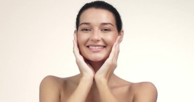 Yanaklarına dokunan kusursuz ciltli, gülümseyen bir kadının yüksek kalite, rafine yakın çekimi. Özel kozmetik markaları, güzellik tanıtımları, cilt bakımı reklamları ve yumuşak odaklı yaşam tarzı görüntüleri için mükemmel..