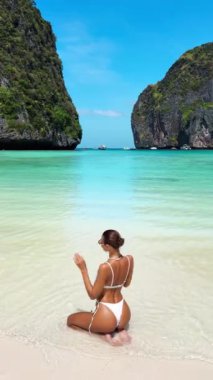 Neşeli kadın manken Tayland 'ın Maya Körfezi kıyısında beyaz bir bikiniyle şakacı poz veriyor. Eğlence, yüksek kalite tropikal plaj videosu seyahat, güzellik ve etkili promosyonlar için ideal.