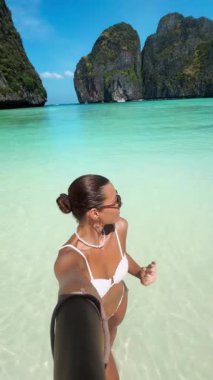 Beyaz bikinili kadın blogcu, tropik Maya Körfezi 'nde özçekim videosu çekiyor, gülümsüyor ve kameraya öpüşüyor. Seyahat, nüfuz, yaşam tarzı ve yaz tanıtım içeriği için ideal.