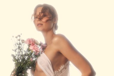 Beyaz dantelli iç çamaşırlı, elinde pembe çiçekler, ılık rüya gibi bir ışıkla yıkanmış beyaz bir kadının sanatsal ve şehvetli portresi. Romantik, moda veya güzellik tanıtım ve editör kullanımı için ideal.