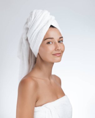 Genç bir kadın cilt bakımını tamamladıktan sonra saçlarını havluya sararak nazikçe gülümsüyor. Güzellik, cilt bakımı, sağlık ve spa tedavileri için mükemmel. Parlayan, sağlıklı