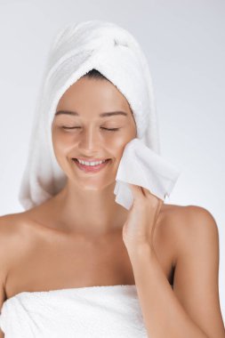 Havlu ambalajlı, gülümseyen ve peçeteli beyaz bir kadın. Kaplıca, doğal güzellik ve kişisel bakım promosyon tasarımları için yüksek kaliteli cilt bakımı afişi.