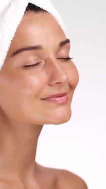 Beyaz bir kadın, cilt bakımından sonra hafifçe gülümser ve yanağına dokunur. Kozmetik reklamlar, markalaşma, kendi kendine bakım yaşam tarzı içeriği ve güzellik ürünü görselleri için mükemmel..