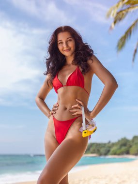 Kırmızı bikinili mutlu kadın turkuaz denizde şnorkel maskesiyle poz veriyor. Kavramsal yüksek kalite görüntü tatil, mayo, sağlık veya tropikal yaşam tarzı reklamları için harika.