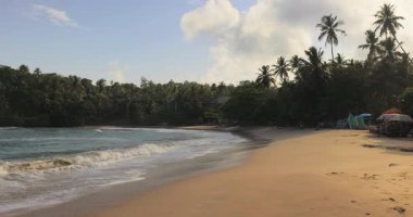 Sri Lanka 'daki Hiriketiya Sahili' nin güzel manzaralı görüntüleri yumuşak dalgalar, altın kum ve tropikal palmiye ağaçları. Seyahat tanıtımları, egzotik yerler ve rahatlama kavramları için mükemmel..