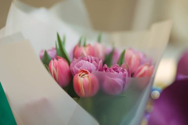 Yumuşak beyaz kağıda sarılı güzel pembe bir lale buketi, romantik jestler, mevsimlik tanıtımlar, çiçek reklamları ve zarif kutlama temalı görseller için mükemmel..