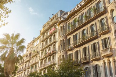 Barcelona 'daki güneşli modernist apartman binaları süslü balkonları ve palmiye ağaçları var. Seyahat tanıtımları, mimari özellikler, editoryal kullanım ve kültürel şehir yaşam tarzı içeriği için ideal.
