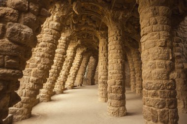 Park Guell 'deki eğimli taş sütunların ve kemerli geçitlerin mimari detayları. Antoni Gaudi tarafından tasarlanan bu site, İspanya 'nın Barcelona kentinde bir numaralı kültür ve turizm merkezidir..