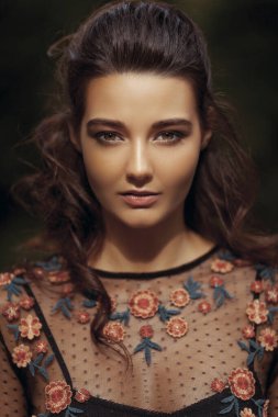 Çiçekli, siyah işlemeli bir bluz giyen, doğal güzelliğini güzelleştiren bir kadının çarpıcı yakın plan portresi. Moda, güzellik ve yazı işleri için mükemmel.. 