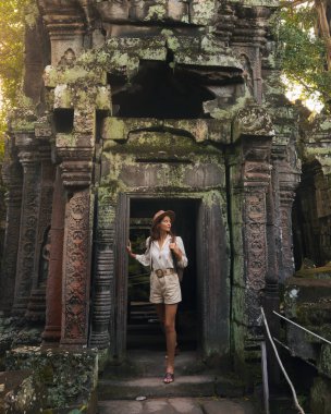 Ta Prohm harabelerinin geçidini keşfeden turist kadın, antik taş oymaları ve orman çevresiyle Kamboçya 'da. Seyahat reklamları, miras, kültür ve mistik macera için yüksek kalite görüntü ideal.