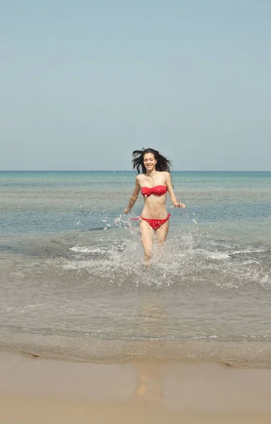 美丽的年轻女子在海滩上从水里跑了出来 — 图库照片
