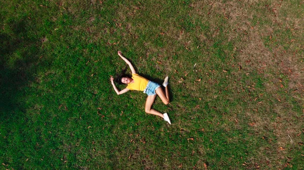 公園の草の上に寝そべっている若い女 — ストック写真