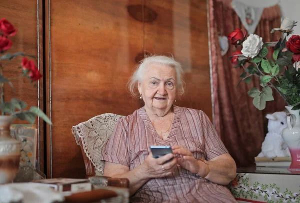 スマートフォンを手にした年配の女性が — ストック写真