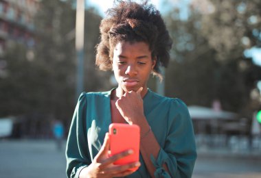 Elinde akıllı telefon olan endişeli genç bir kadın.