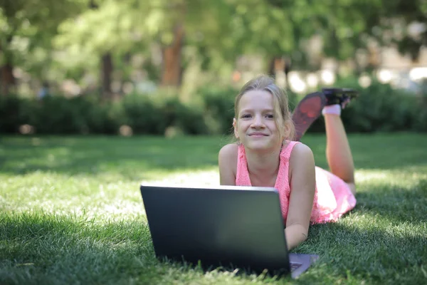 在公园里拿着电脑的小女孩 — 图库照片