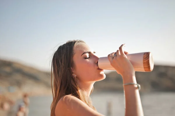 Νεαρή Γυναίκα Πίνει Από Ένα Μπουκάλι Νερό Στην Παραλία — Φωτογραφία Αρχείου