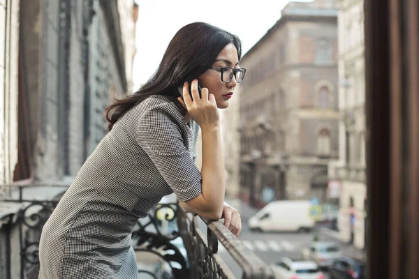 年轻的亚洲女人在阳台上通过电话交谈 — 图库照片