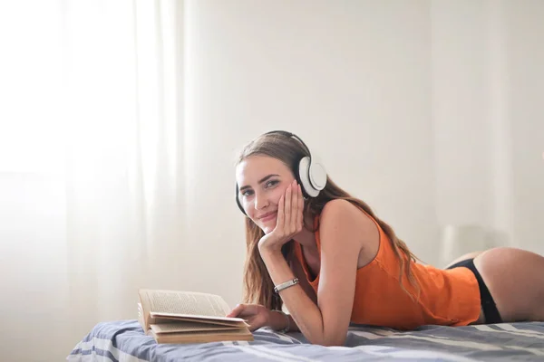 ベッドの上で本を読んでいる若い女性が — ストック写真
