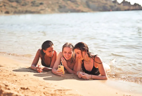 Τρία Κορίτσια Ξαπλωμένα Στην Παραλία Ένα Smartphone — Φωτογραφία Αρχείου