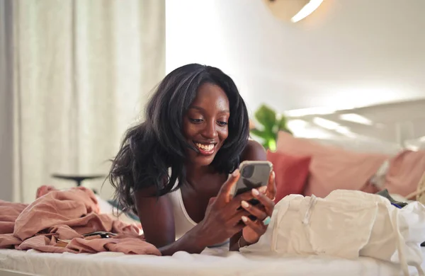Yatakta Uzanmış Bir Kadın Akıllı Telefon Kullanıyor — Stok fotoğraf
