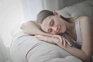 Genç kız bir kanepenin arkasına yaslanarak uyuyor.