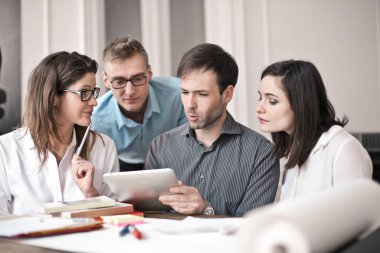 Ofiste elinde tabletle çalışan bir grup genç.