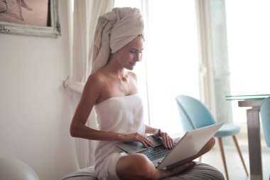 Kadın evinde dizüstü bilgisayar kullanıyor.