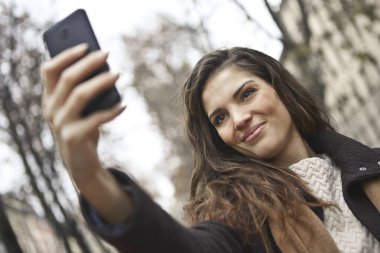 Güzel kız sokakta selfie çekiyor.