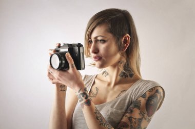 Dövmeli genç bir kadın fotoğraf çekiyor.