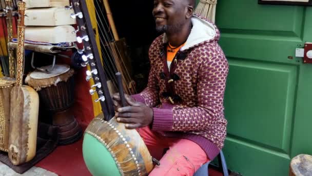 セネガル人男性が伝統的なコラの弦楽器を演奏しています 伝統的なアフリカ アフリカ音楽は 路上で 結婚式やフェスティバルでしばしば演奏された 4K映像について — ストック動画
