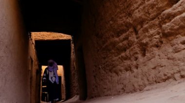 Geleneksel giyinmiş Faslı bir Bedevi adam mavi gandoura giyiyor ve Mhmaid, Fas 'ta Kasbah' ın içinde türban yürüyor. Güney Fas 'ın otantik kırsal manzarası. 4k. 