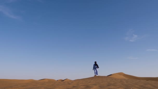 在摩洛哥的Erg Lihoudi沙漠 一名身穿蓝色长袍 头戴德拉巴和头巾的传统摩洛哥男子走在沙丘上 摩洛哥南部真正的沙漠景象 — 图库视频影像