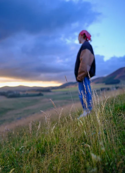 一个女孩在苏格兰的山坡上 在夕阳西下的一个夏夜 专心致志地看着前方的草地 — 图库照片