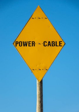 A Bright Yellow Warning Sign For A Power Cable clipart