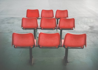 Bekleme alanında üç sıra rahatsız edici turuncu plastik sandalye.