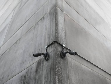 Kentsel gözetim ve gözlem için bir beton binanın köşesine monte edilmiş iki siyah güvenlik kamerası.