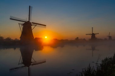 Hollanda 'nın Kinderdijk şehrinde güneş doğmadan hemen önce renkli gökyüzü olan geleneksel Hollanda yel değirmenleri