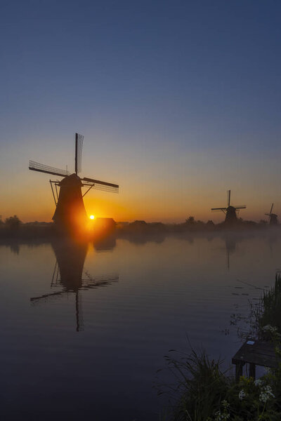 Traditional Dutch windmills with a colourful sky just before sunrise in Kinderdijk, The Netherlands