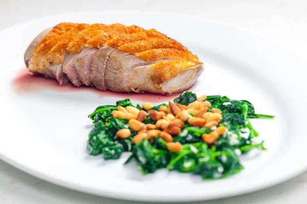 roasted duck breast served with salad of spinach leaves and pine nuts