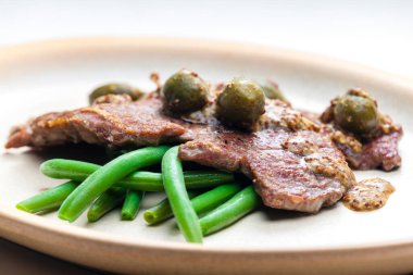 Kapari ve yeşil fasulyeli hardal soslu domuz bifteği.