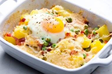 Füme etle pişirilmiş patates, taze bezelye ve fırında yumurta ile servis edilen çedar peyniri.