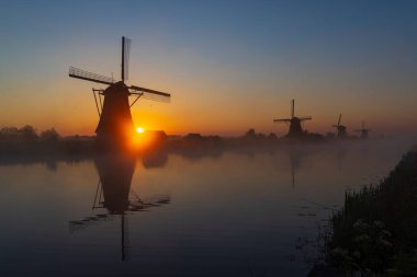Hollanda 'nın Kinderdijk şehrinde güneş doğmadan hemen önce renkli gökyüzü olan geleneksel Hollanda yel değirmenleri