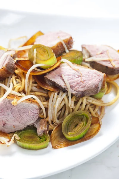 slices of duck breast with noodles, vegetables and bamboo shoots