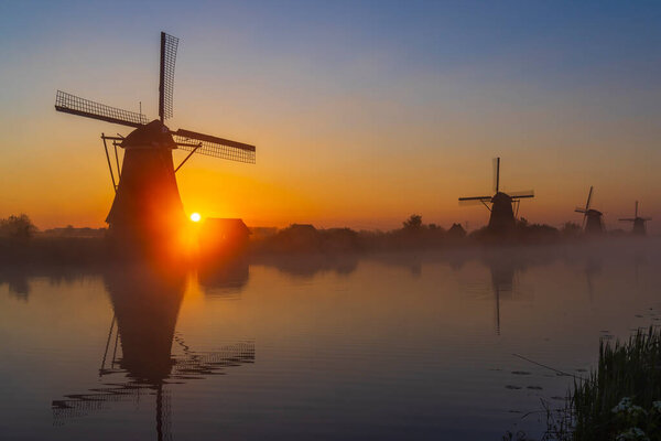Traditional Dutch windmills with a colourful sky just before sunrise in Kinderdijk, The Netherlands