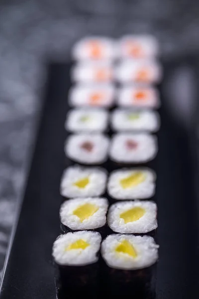 黒石の背景に魚介類を盛った寿司ロールのセット — ストック写真