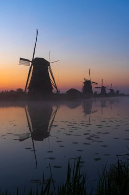 Hollanda 'nın Kinderdijk şehrinde güneş doğmadan hemen önce renkli gökyüzü olan geleneksel Hollanda yel değirmenleri