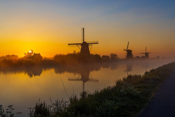 Traditional Dutch windmills with a colourful sky just before sunrise in Kinderdijk, The Netherlands
