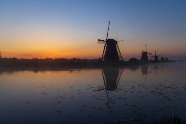 Hollanda 'nın Kinderdijk şehrinde güneş doğmadan hemen önce renkli gökyüzü olan geleneksel Hollanda yel değirmenleri